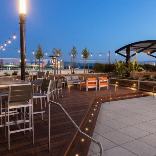 A perfect fit for the whole family a deck with chairs and tables on it by a body of water